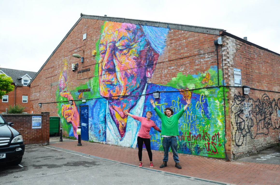 Artists Mani Manson-Reeves & Cathrin Poppensieker stand in front of colourful David Attenborough mural