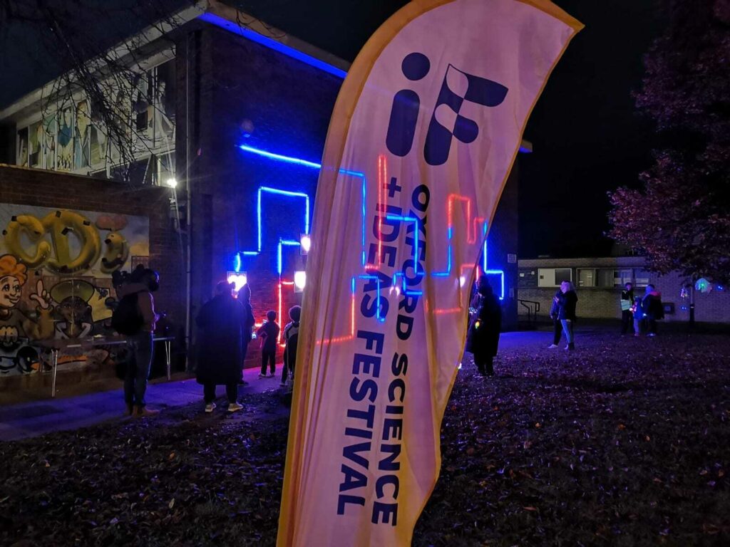People interact with the responsive LED artwork behind IF Oxford flag