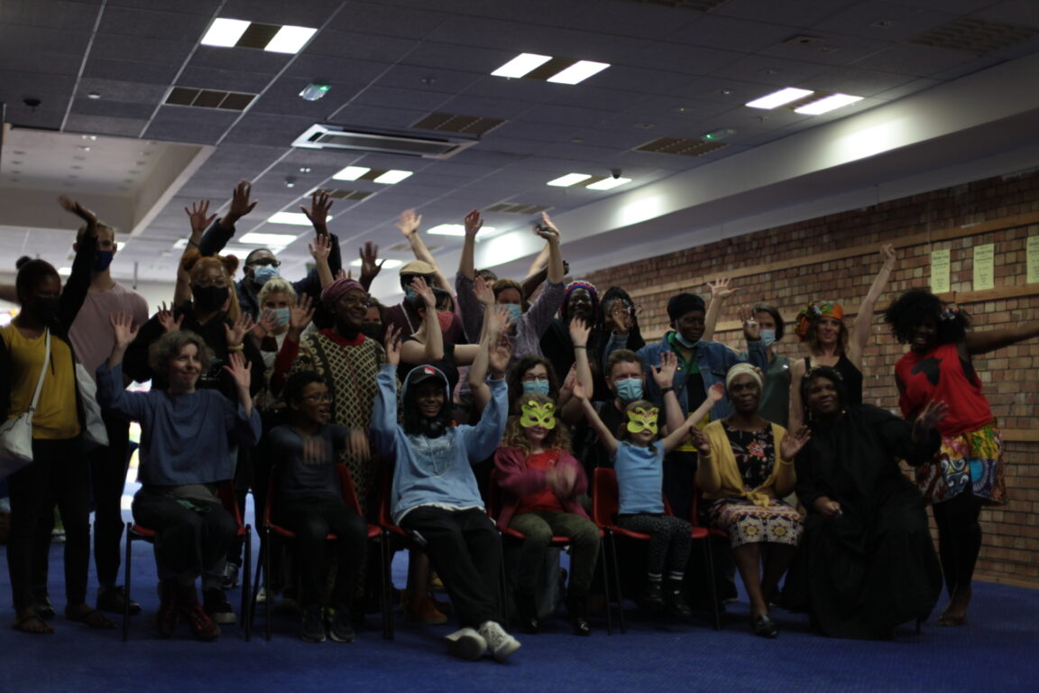An intergenerational group of people at the discovery day in Templars Square with their hands up