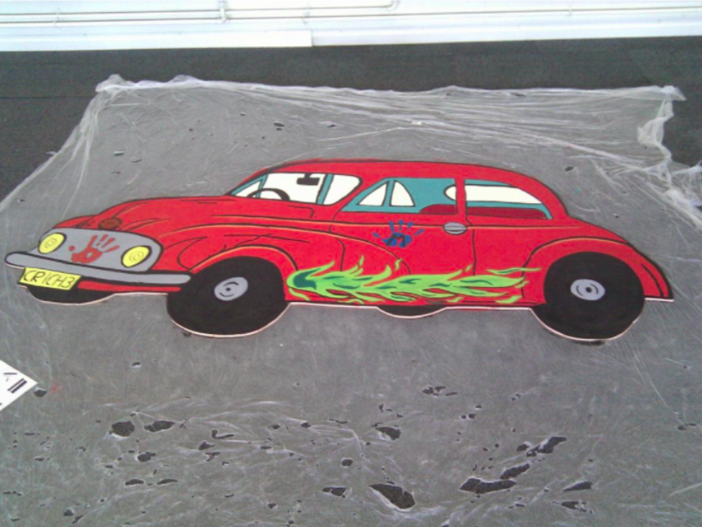 Painting of red car with green flames on the side on mural.