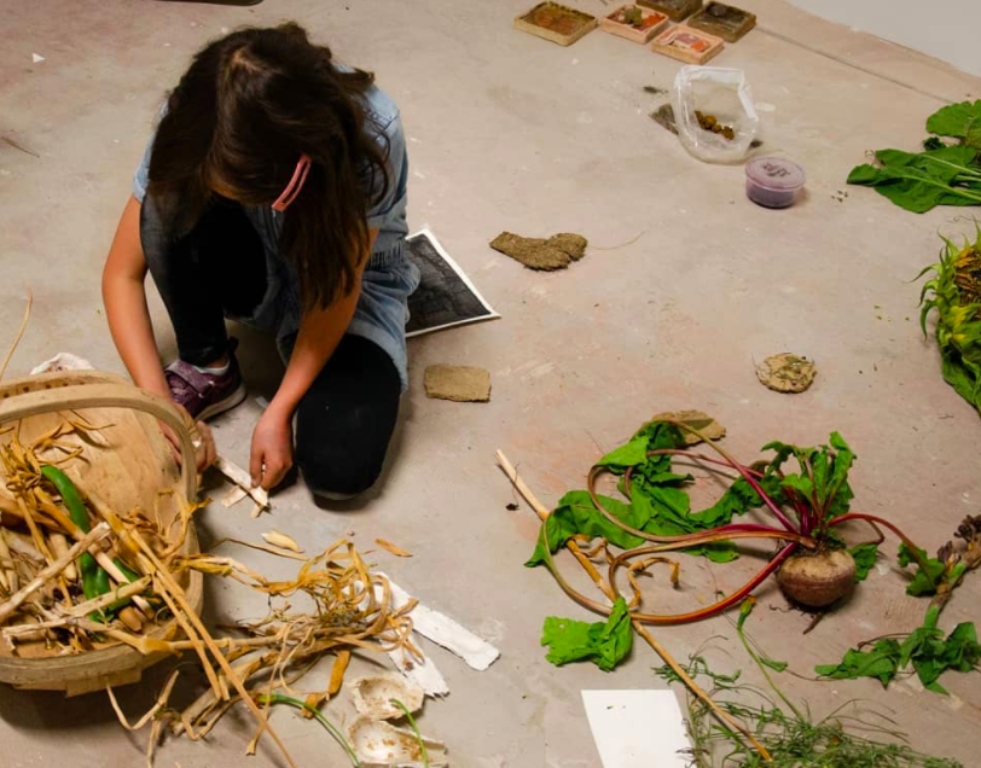 Young girl working on the floor on a project with natural materials.