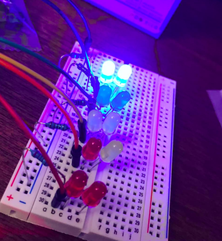 Set of multi-coloured wires attached to coding device in the dark.
